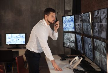 Male security guard using radio transmitter in surveillance room
